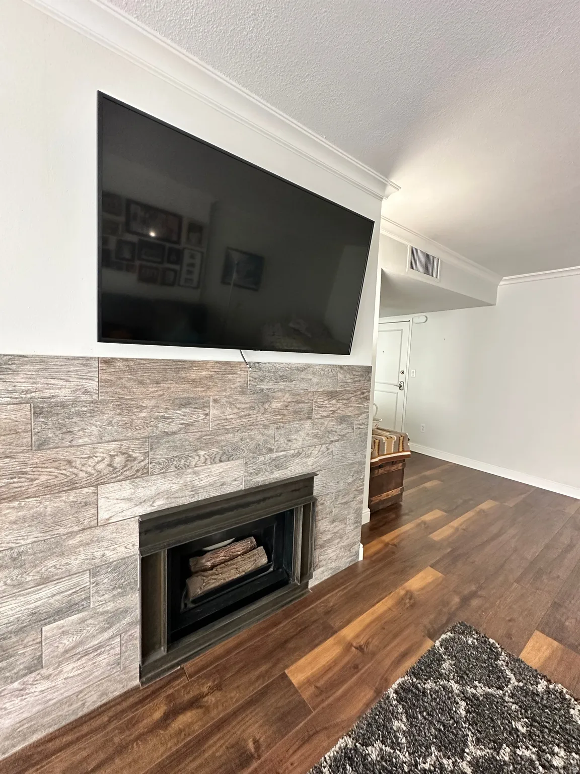 Fireplace featuring a wood-look tile surround and a dark-finished firebox