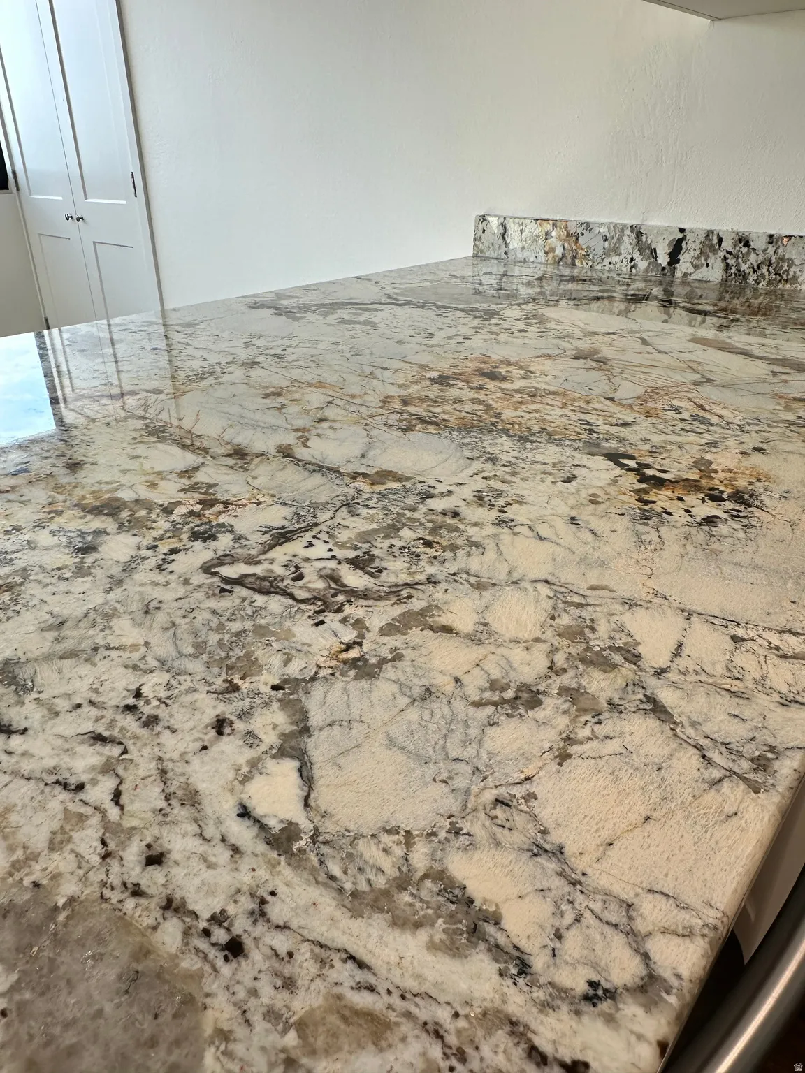 Polished natural stone countertop with intricate veining, featuring a matching backsplash