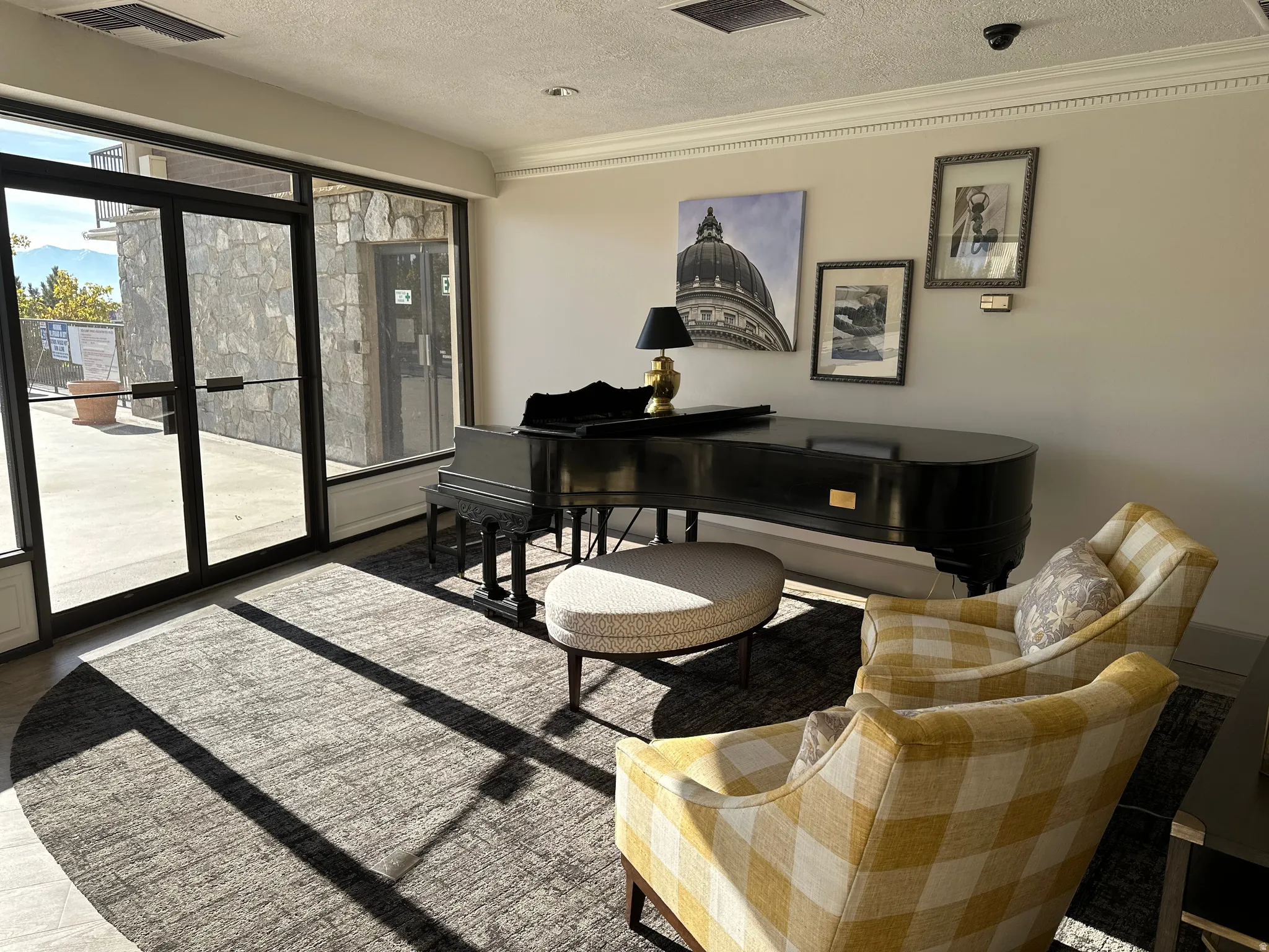 Spacious common area featuring a grand piano, decorative crown molding, and large glass entry doors