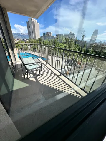 Private balcony with concrete flooring and metal railings overlooking a swimming pool