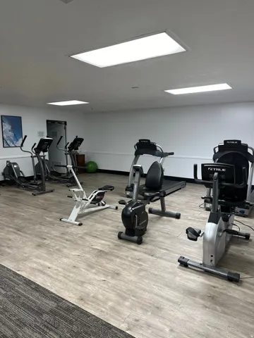 Dedicated fitness area featuring wood-finish flooring, white walls, and bright overhead lighting