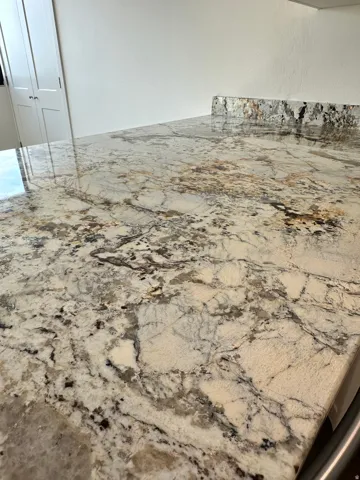 Polished natural stone countertop with intricate veining, featuring a matching backsplash