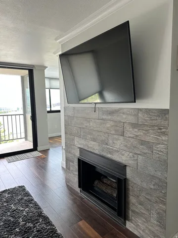 Fireplace featuring wood-look tile surround and dark wood-finish flooring