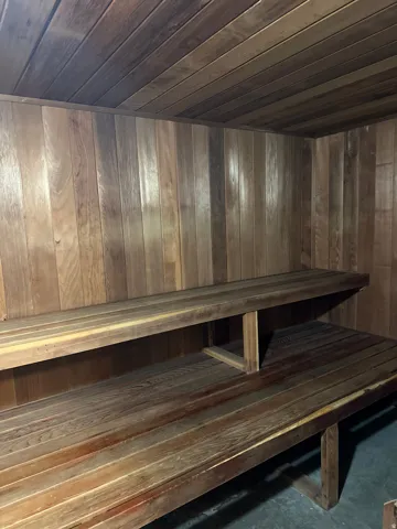 Custom sauna room featuring wood paneling, slatted wood benches, and a two-tiered seating design