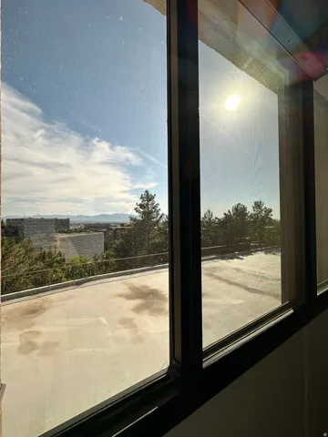 Expansive window framing a distant mountainous landscape and a large exterior patio