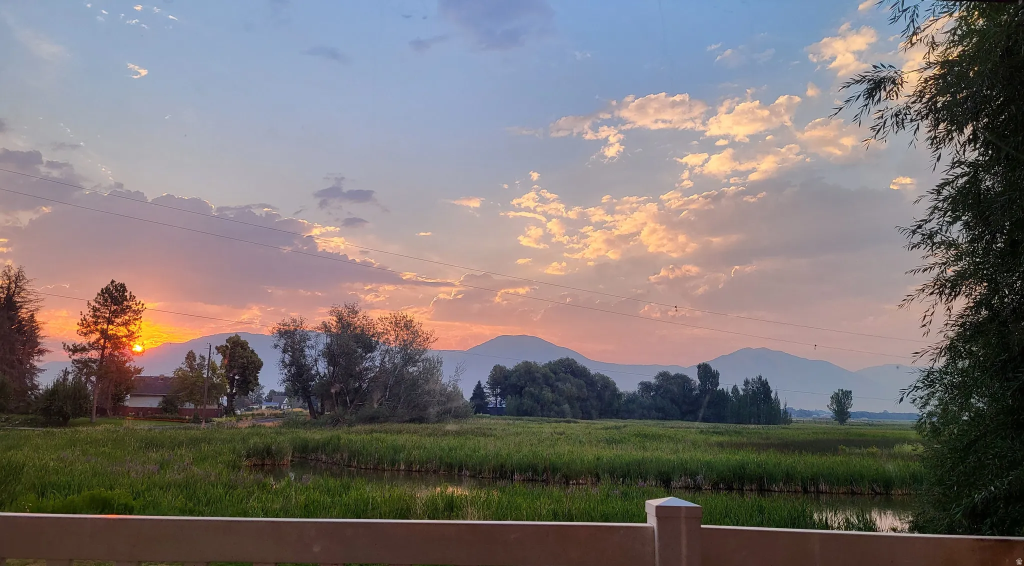 Sunrise looking at expansive natural surroundings featuring a pond, distant mountains, and varied trees