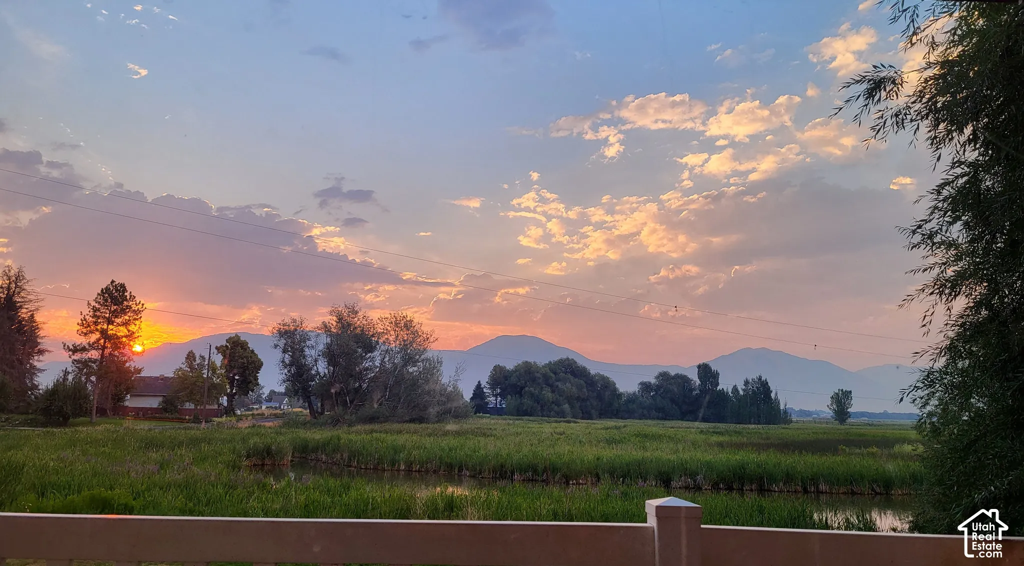 Sunrise looking at expansive natural surroundings featuring a pond, distant mountains, and varied trees
