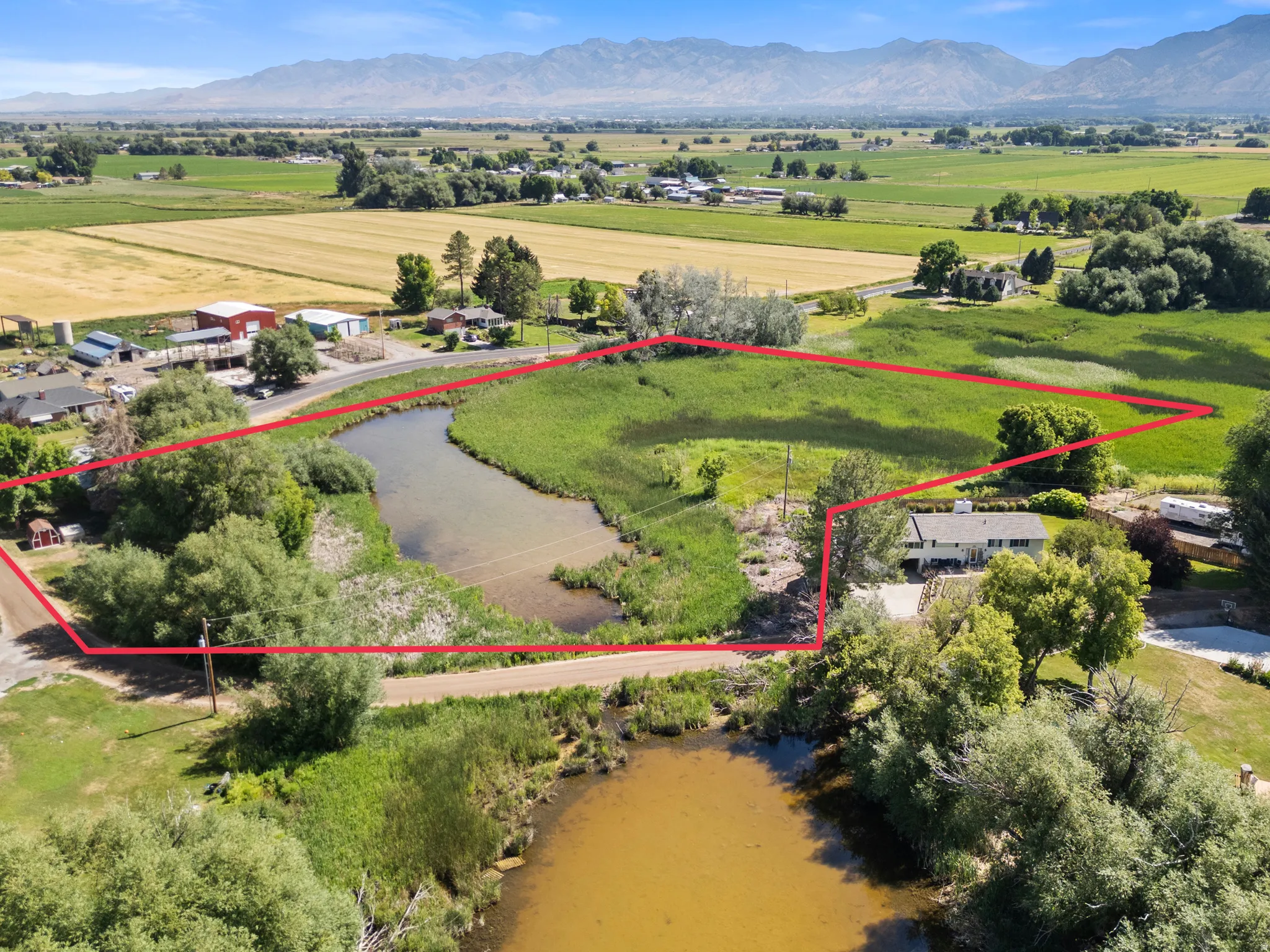 Expansive acreage featuring a natural water body, a single-family residence, and abundant mature trees
