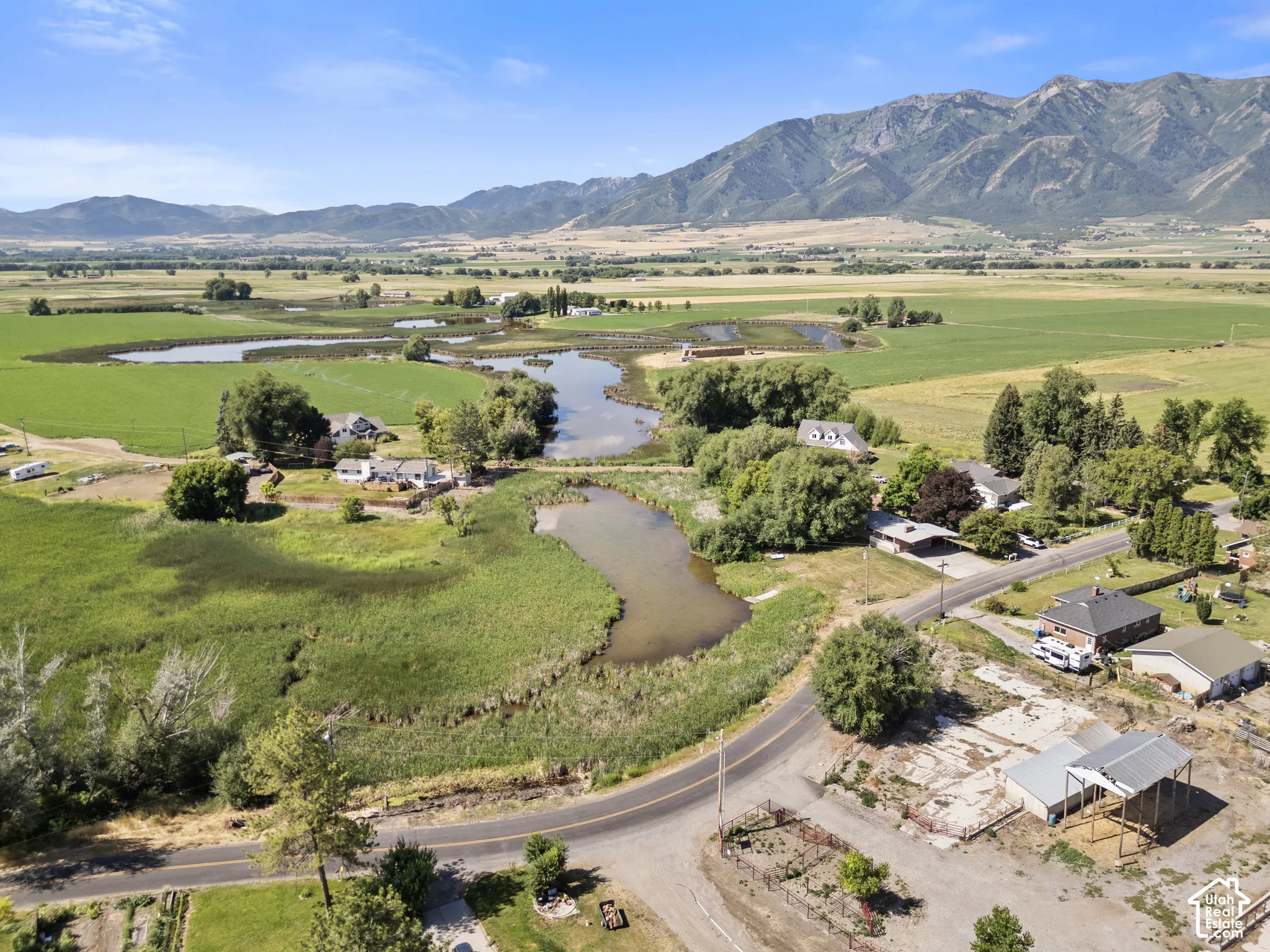 Expansive rural landscape featuring a road, pond, and distant mountains