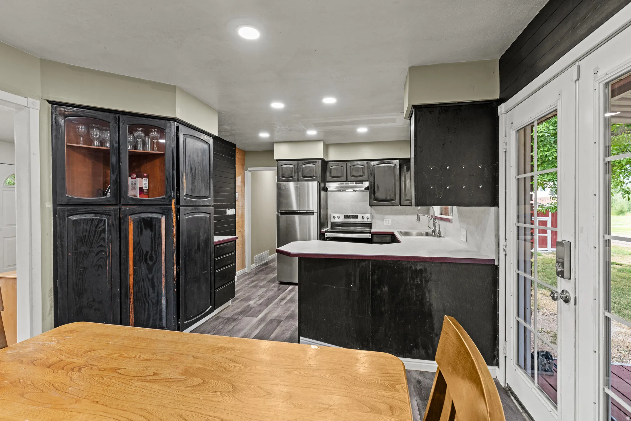 Kitchen featuring wood-finish flooring, recessed lighting, and wood cabinetry with glass-front display sections