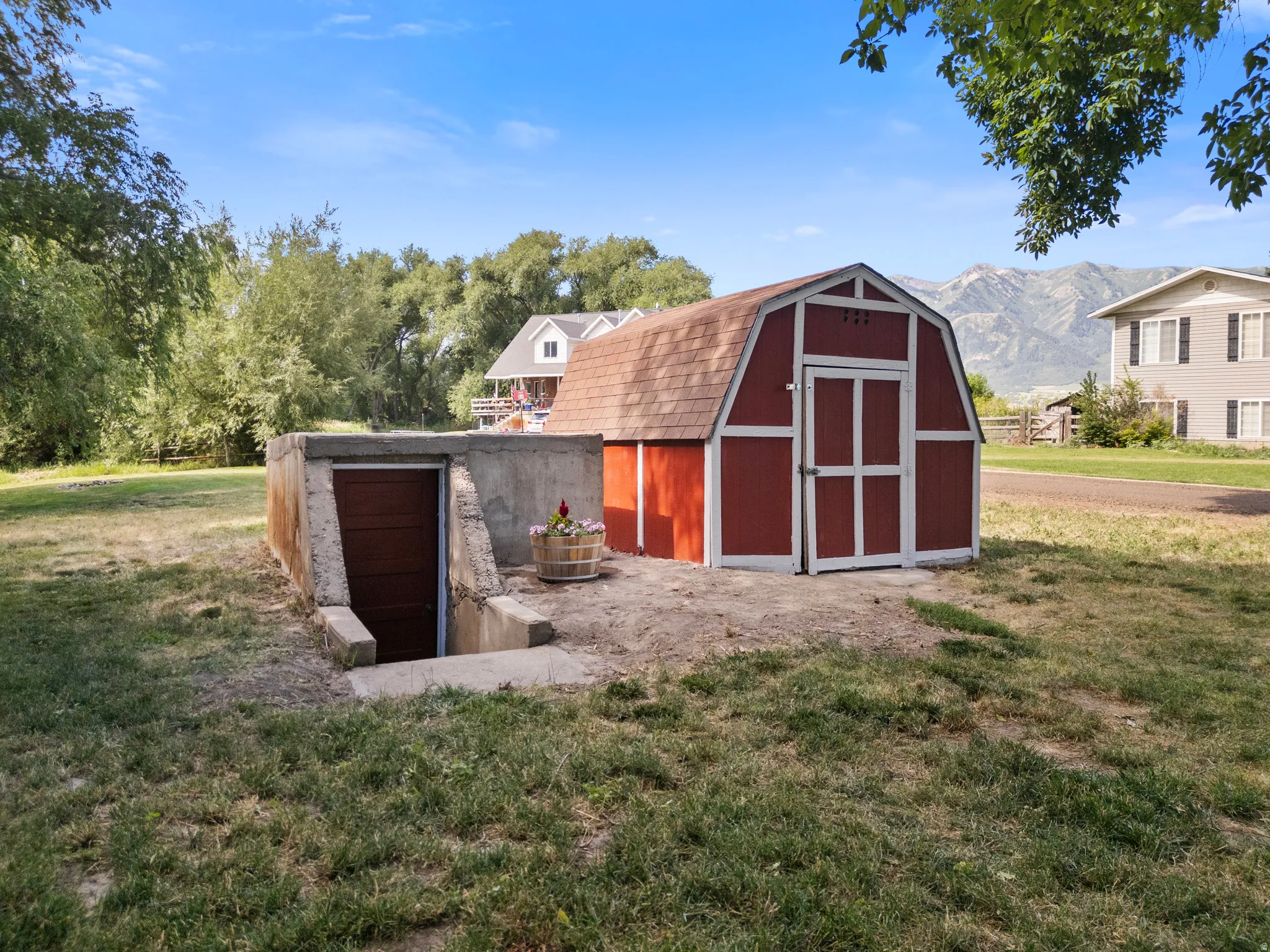 Red barn-style shed with white trim and shingle roofing. Along side inground storage.