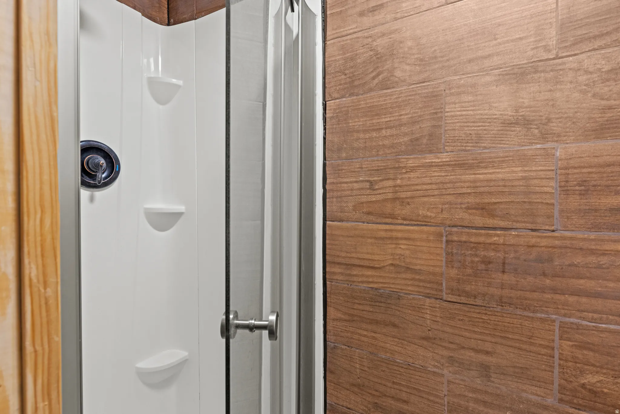 Shower enclosure featuring a white panel surround with integrated shelving