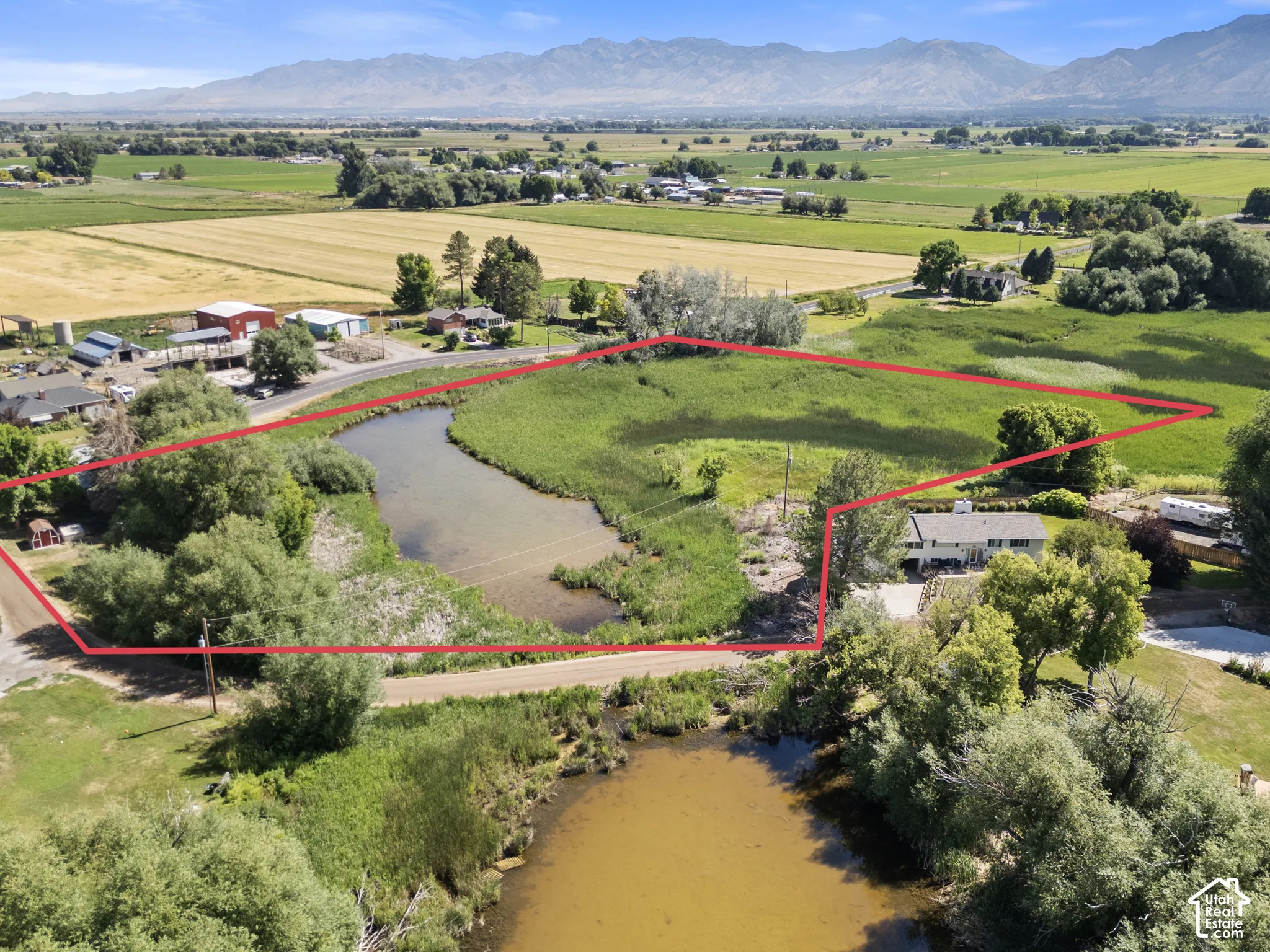 Expansive acreage featuring a natural water body, a single-family residence, and abundant mature trees