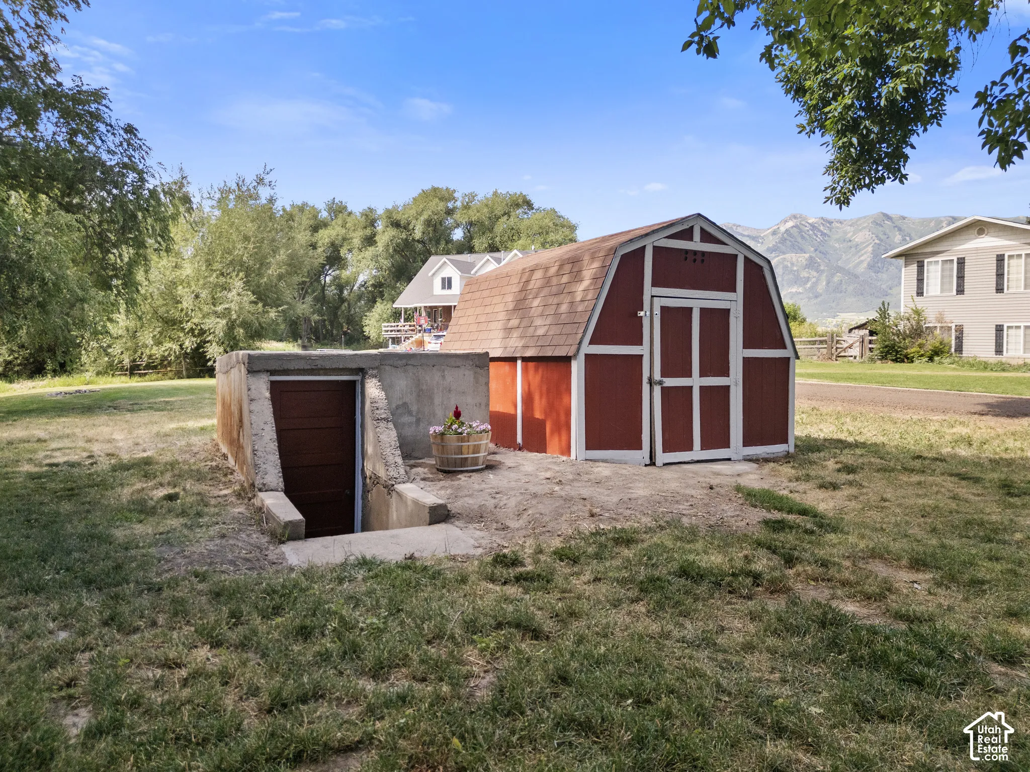 Red barn-style shed with white trim and shingle roofing. Along side inground storage.