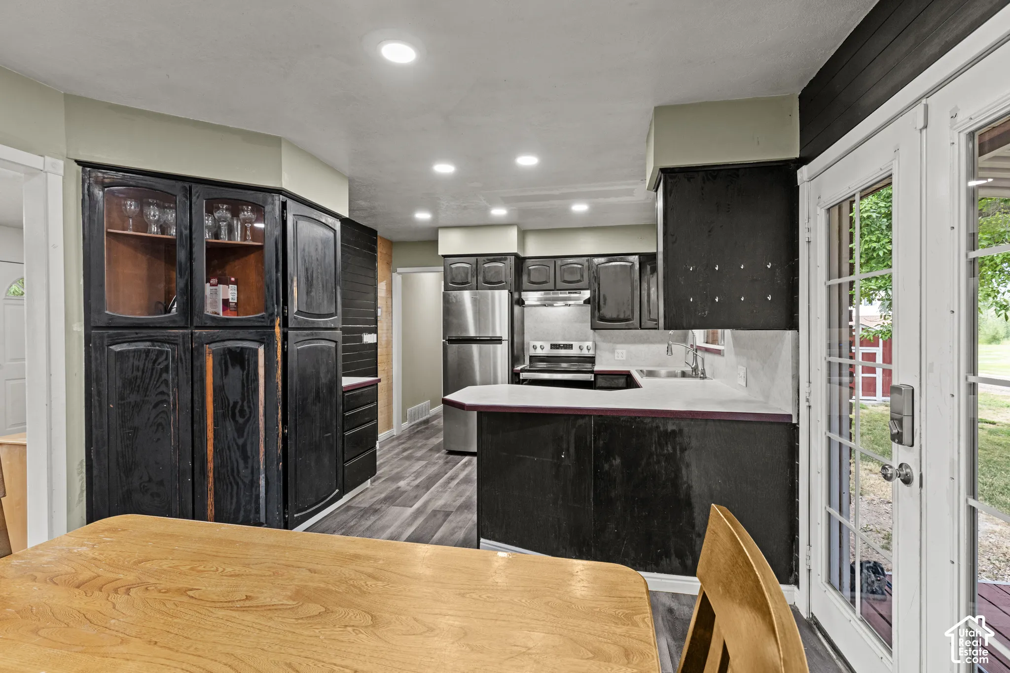 Kitchen featuring wood-finish flooring, recessed lighting, and wood cabinetry with glass-front display sections