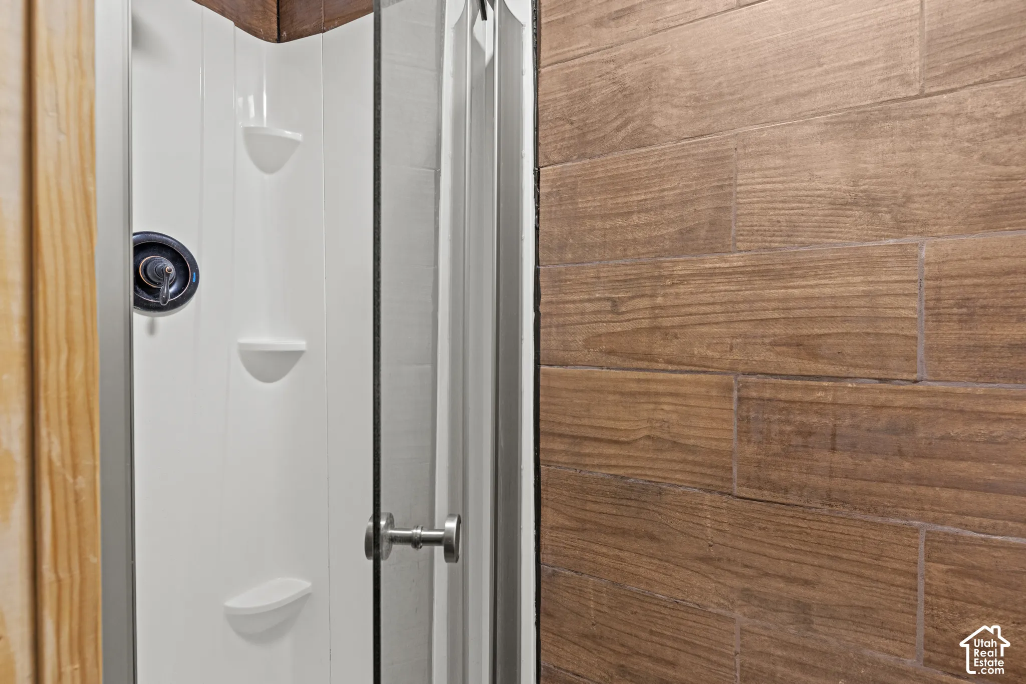 Shower enclosure featuring a white panel surround with integrated shelving
