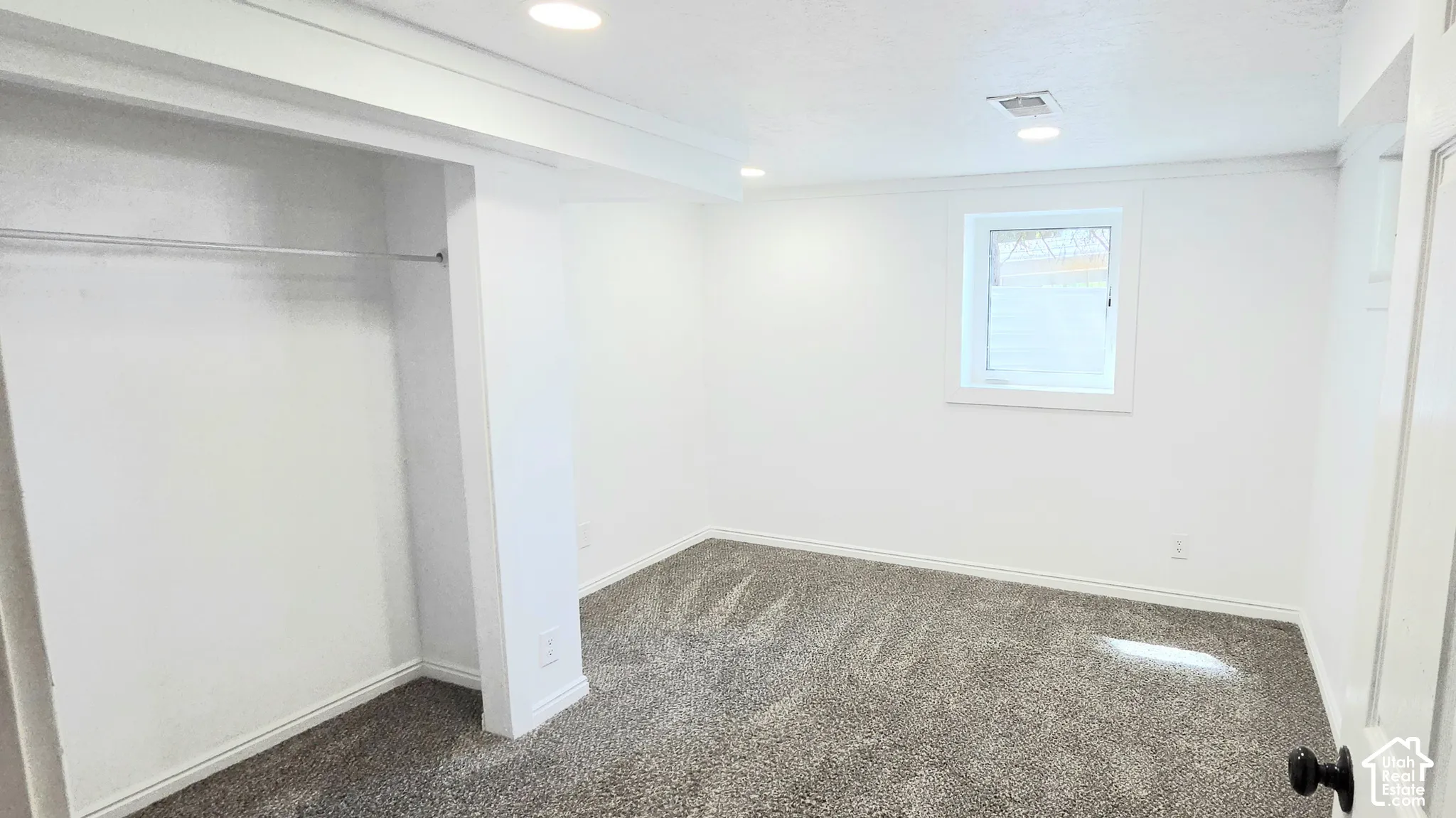 Recessed lighting, white walls, carpet, and a window with white trim