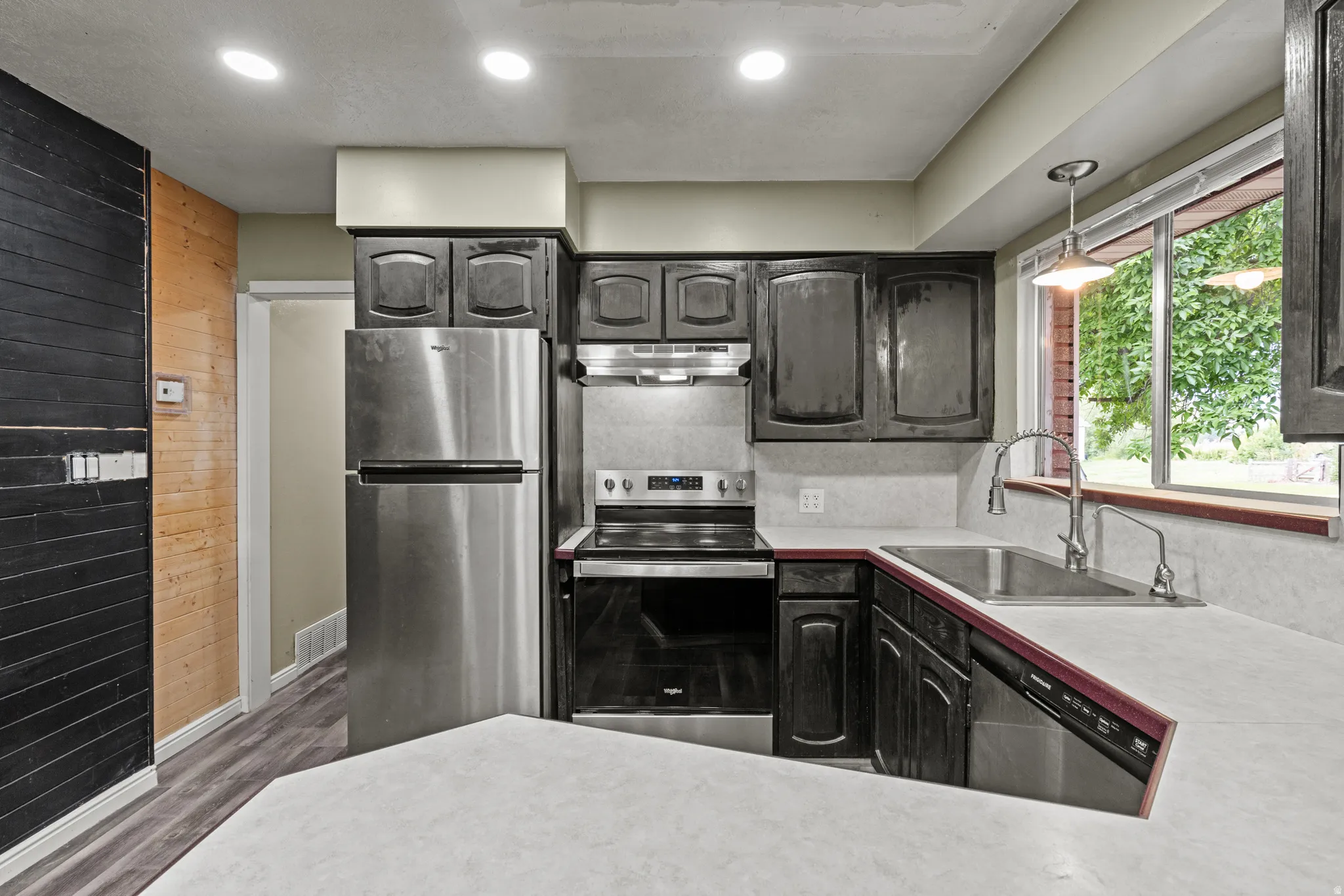 Kitchen featuring cabinetry, stainless steel appliances, countertops, and wood-finish flooring