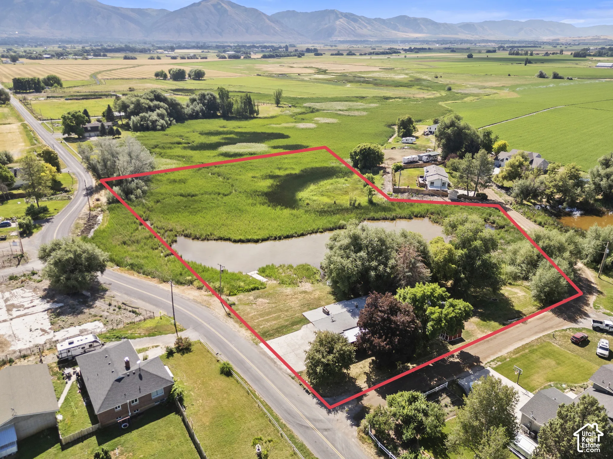 Expansive parcel featuring a natural pond, surrounding wetlands, mature trees, and a distant mountain backdrop