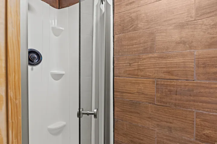 Shower enclosure featuring a white panel surround with integrated shelving
