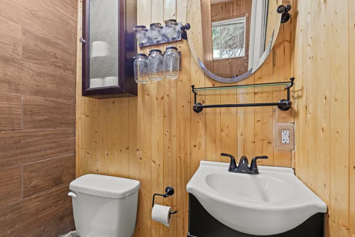 Corner pedestal sink with black hardware, flanked by natural wood plank walls