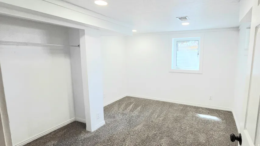 Recessed lighting, white walls, carpet, and a window with white trim