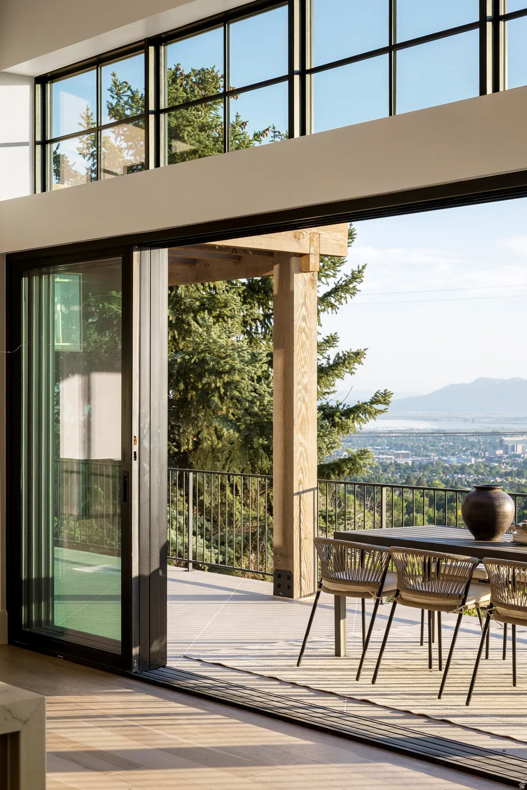 Seamless indoor-outdoor living with floor-to-ceiling sliding glass doors opening onto a composite wood-finish deck