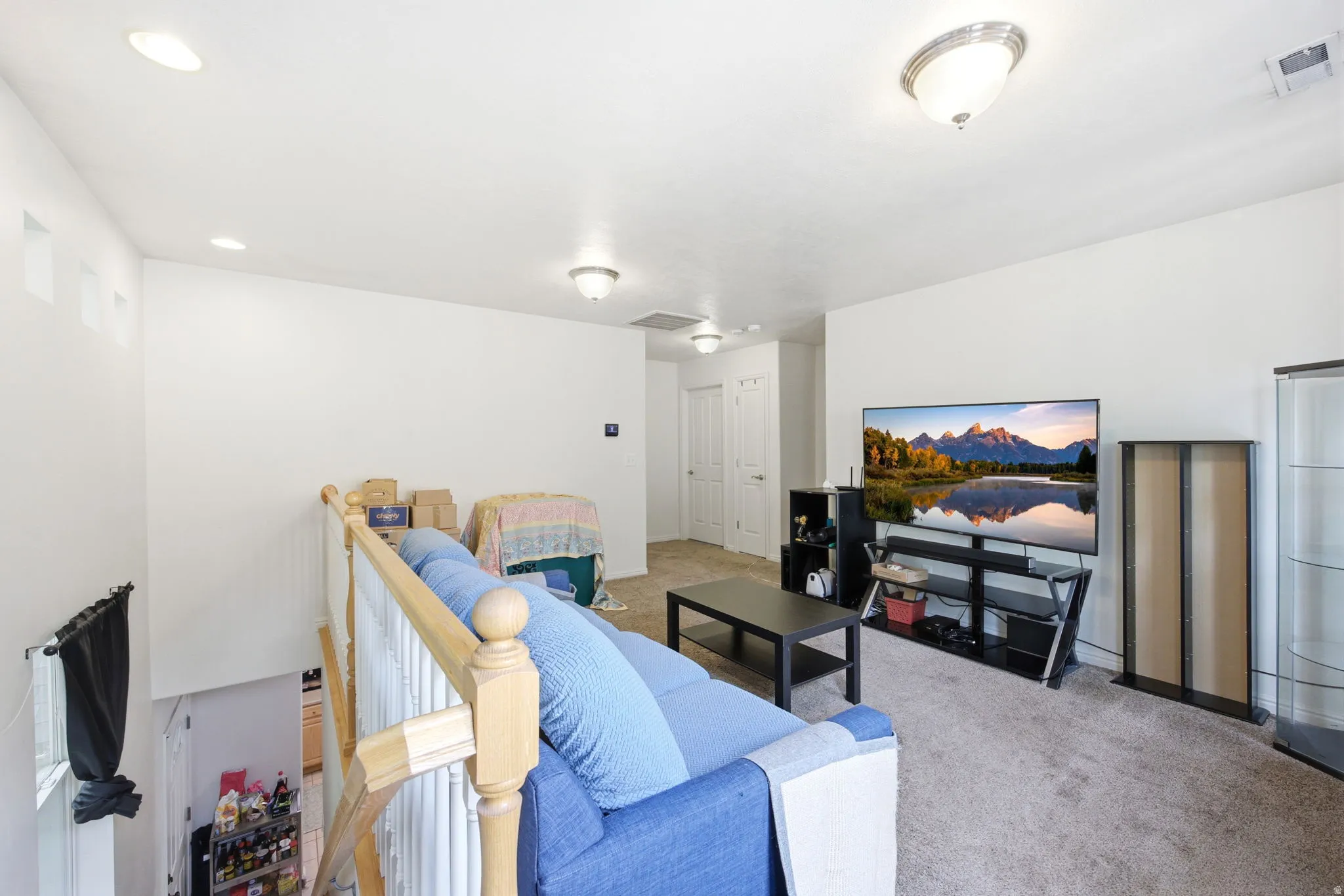 Upper-level landing featuring carpeted flooring and white walls