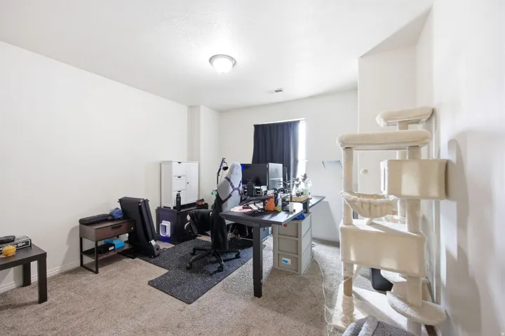 Carpeted interior space with white walls, a single window featuring dark drapes, and a ceiling-mounted light fixture