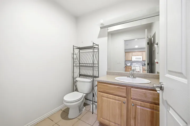 Bathroom featuring a wood-finish vanity with a built-in sink, a large wall-mounted mirror, and tile flooring