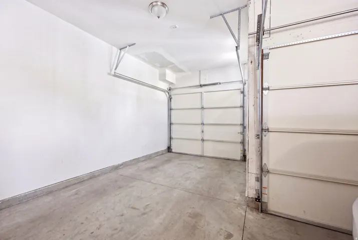 Attached two-car garage featuring a concrete floor, white walls, and overhead lighting