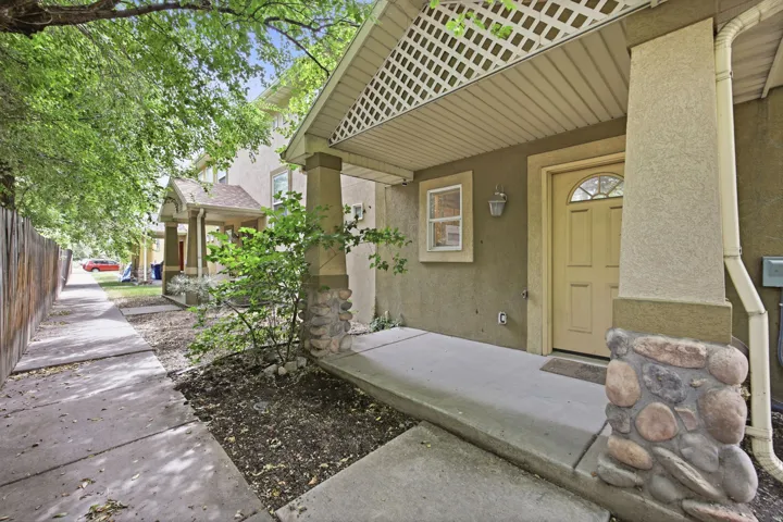Front entry featuring a covered porch, stone-accented columns, and a paneled door with an arched glass insert