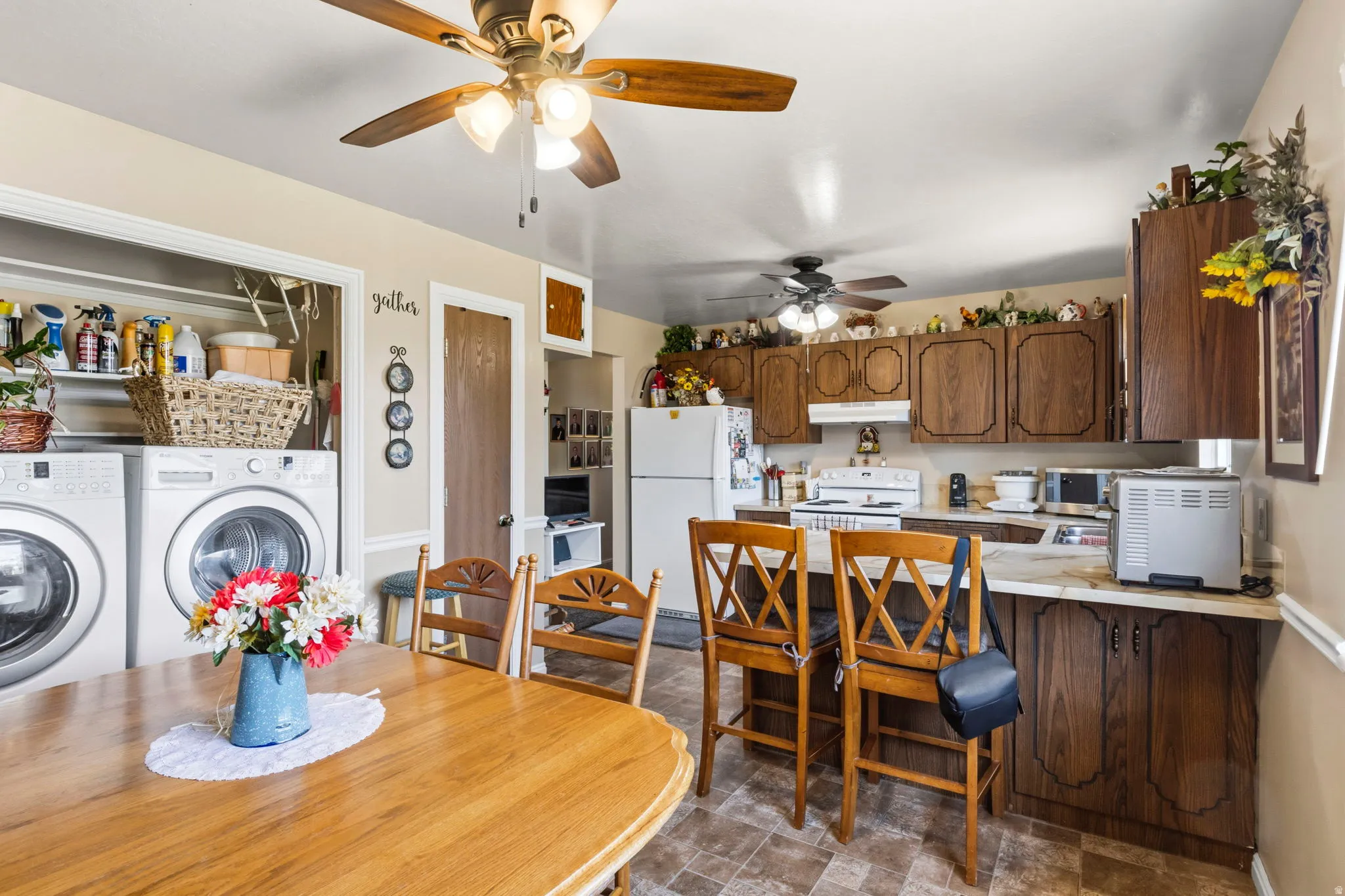 Combined kitchen and laundry area featuring wood-finish cabinetry, laminate countertops, and resilient flooring