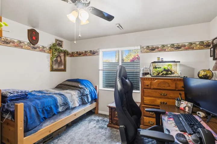 Bright room featuring a window with horizontal blinds, a ceiling fan with integrated lighting, and plush carpeting