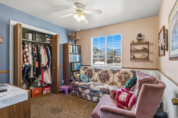 Carpeted room featuring a ceiling fan, a window with horizontal blinds, and a built-in closet with bi-fold doors