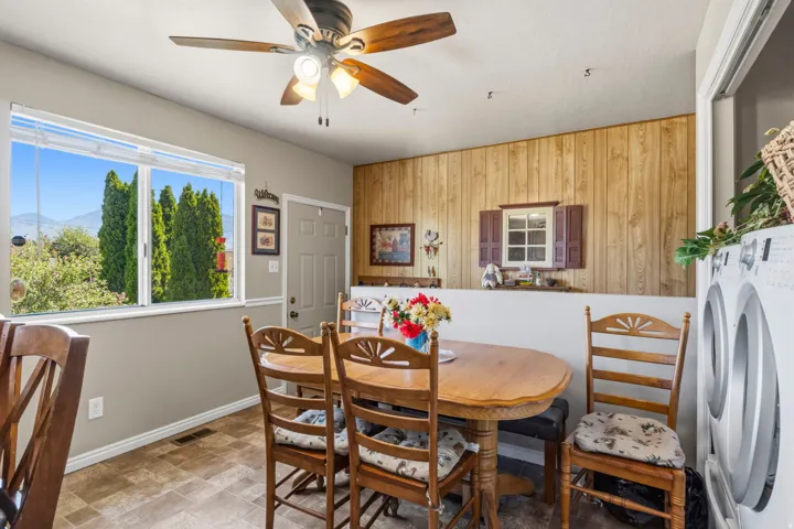 Dining area featuring wood-finish flooring, a ceiling fan with integrated lighting, and a window with white blinds