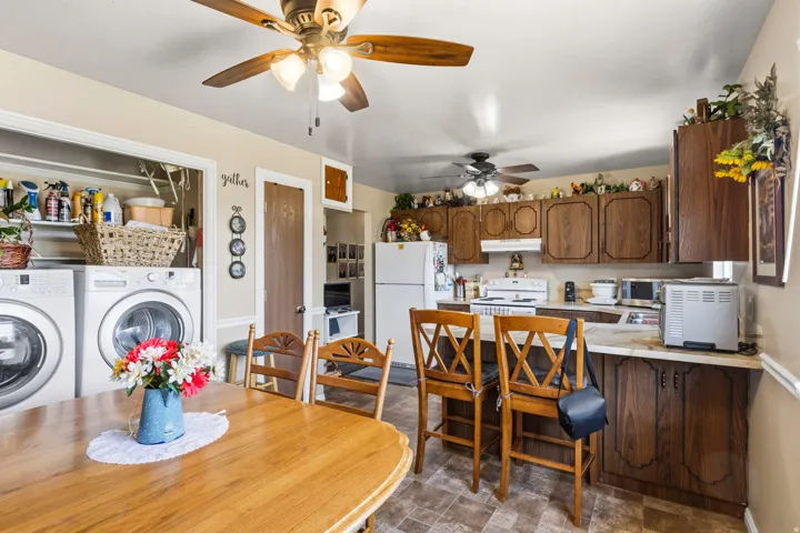 Combined kitchen and laundry area featuring wood-finish cabinetry, laminate countertops, and resilient flooring