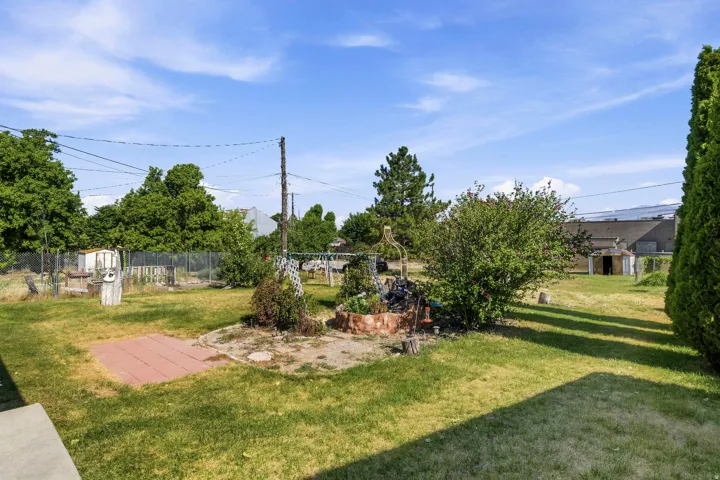 Expansive backyard featuring a central garden area with brick edging, mature trees, and a flat concrete patio area