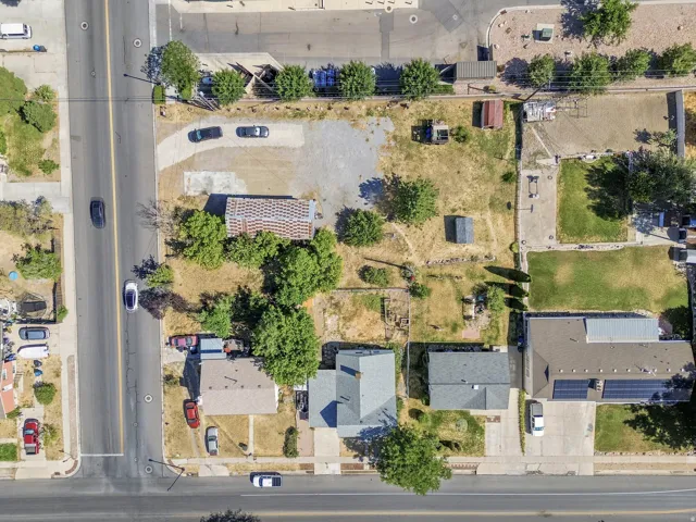 Aerial view showcasing a property with a gray-shingled roof, a mature tree, and surrounding landscaping