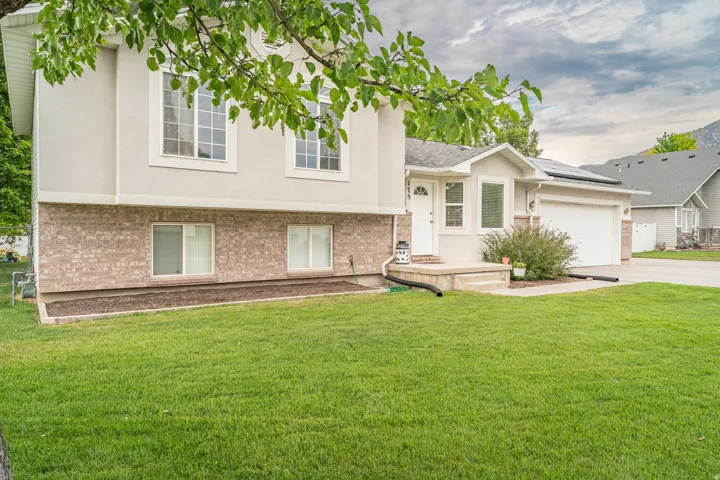 Two-story residence featuring a brick and stucco facade, an attached garage, a covered front entry, and a manicured lawn