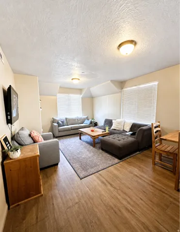Spacious living area featuring wood-finish flooring, textured ceilings, and recessed lighting