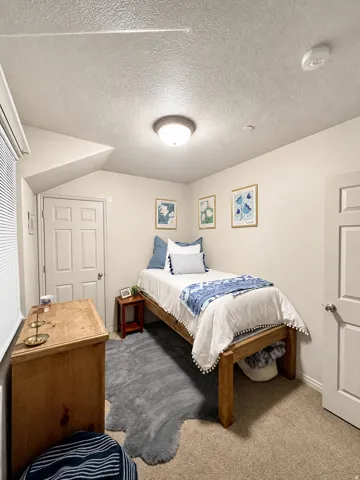 Carpeted room featuring neutral-toned walls, a white paneled door, and a flush-mount ceiling light fixture