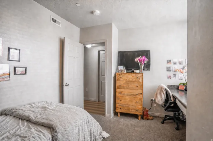 Neutral-toned room featuring a doorway with a panel door, grey textured walls, and grey carpeting