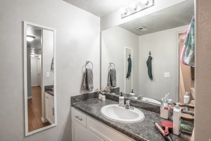 Bathroom featuring a single vanity with a white basin, dark countertop, and white cabinetry