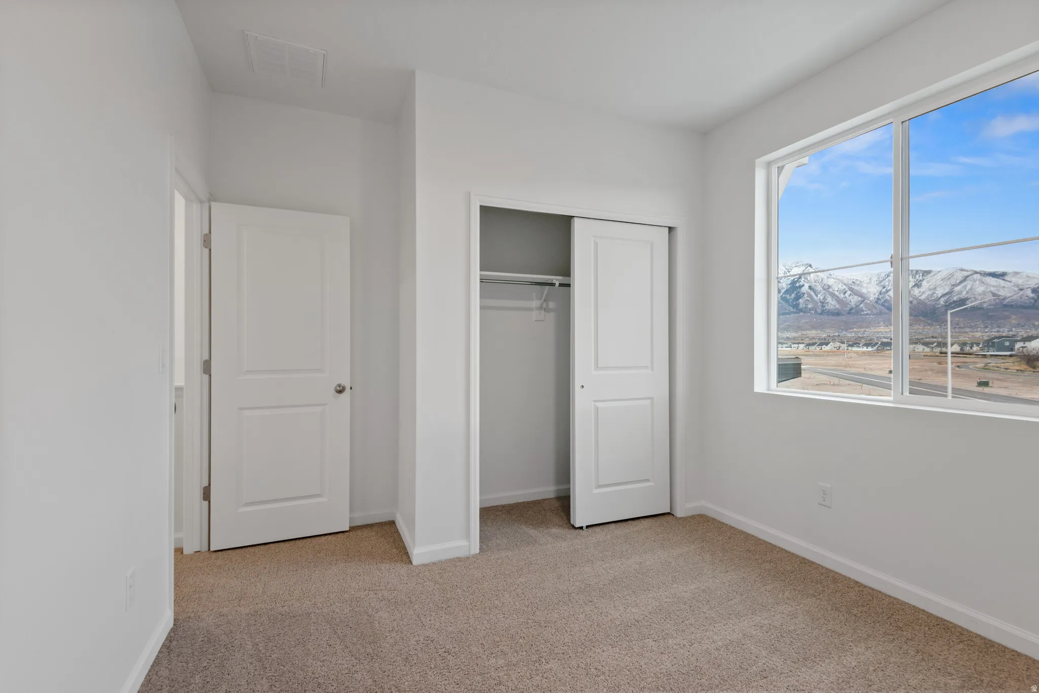 Bedroom featuring light-toned carpeting and a large window