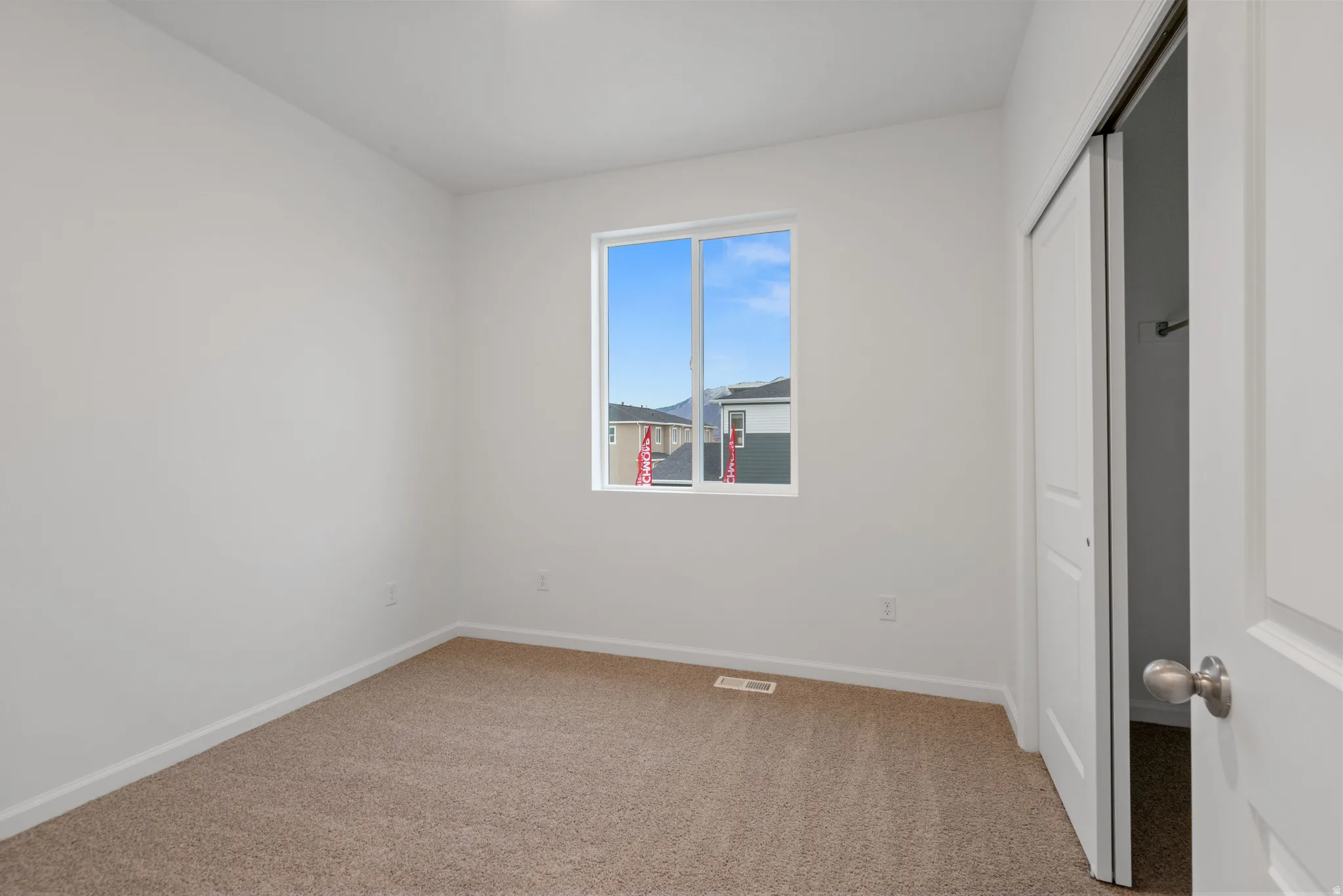 Neutral-toned carpet flooring in a room featuring white walls and a white-trimmed window