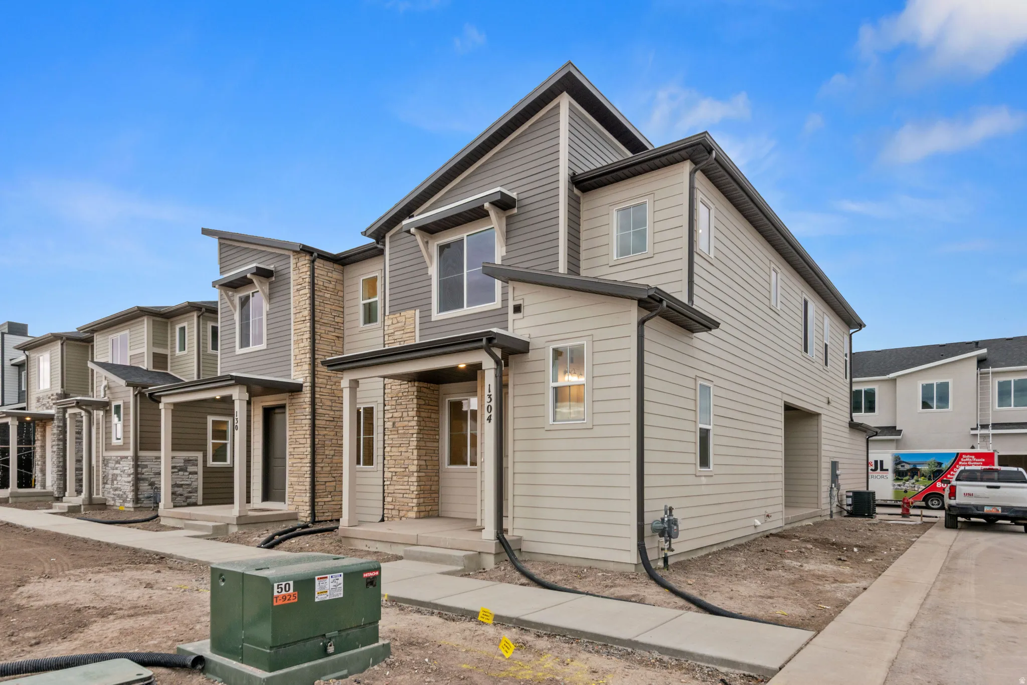 Modern townhome exterior with mixed material siding, stone accents, and a covered front porch