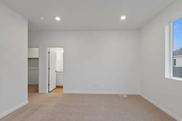 Spacious room featuring neutral carpeting, recessed lighting, and a large window