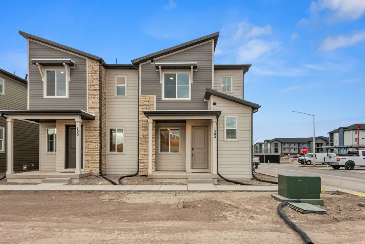 Contemporary townhome exterior featuring multi-toned siding, stone accents, and a distinctive sloped roofline