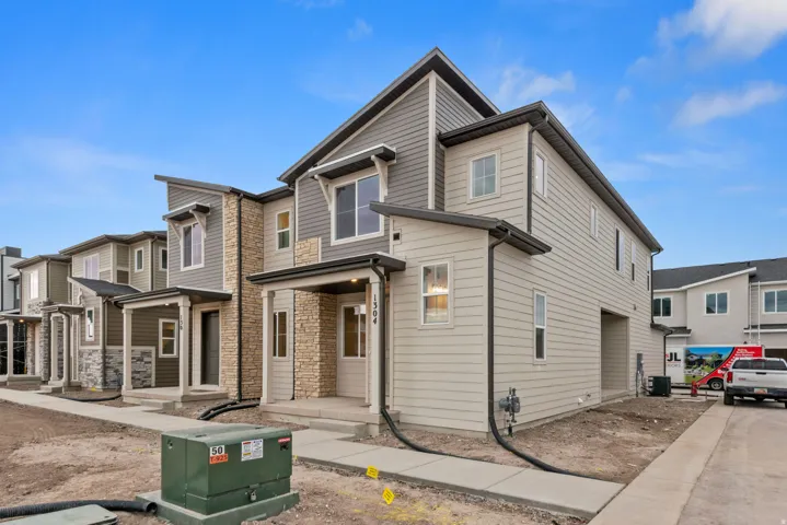 Modern townhome exterior with mixed material siding, stone accents, and a covered front porch